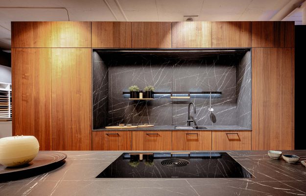 Hochwertige Einbauküche mit schwarzer Marmor-Rückwand, Holzfronten und offenem Regalelement – exklusives Küchendesign im Showroom Göttingen.