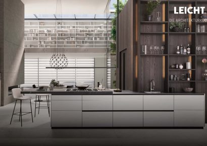 LEICHT Architekturküche mit heller Kochinsel, dunklem Holzregal und großem Tageslichteinfallsbereich – exklusive Premiumküche im modernen Loftambiente.