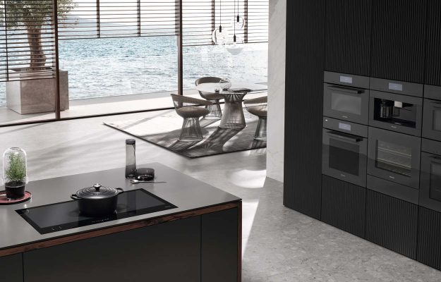 Elegante Küche mit Kochinsel, Meerblick und Premium-Einbaugeräten – moderne, puristische Wohnküche mit exklusiver Ausstattung.