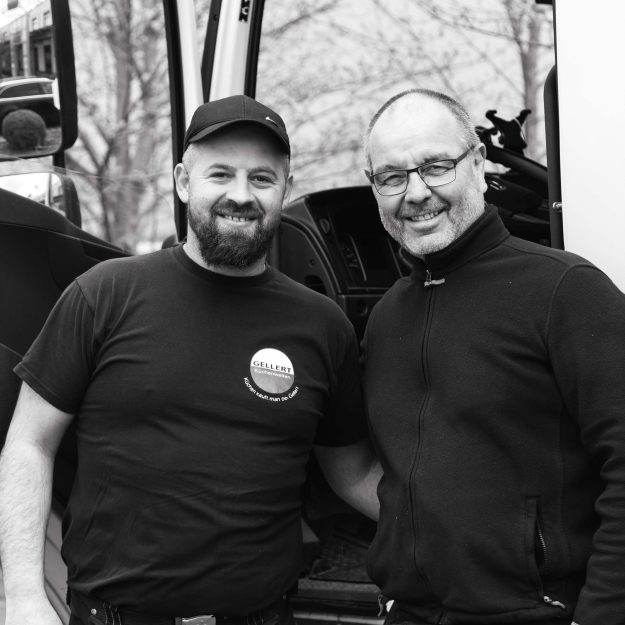 Zwei freundliche Monteure von Gellert Küchenwelten vor einem Firmenfahrzeug – professionelle Lieferung und fachgerechte Montage