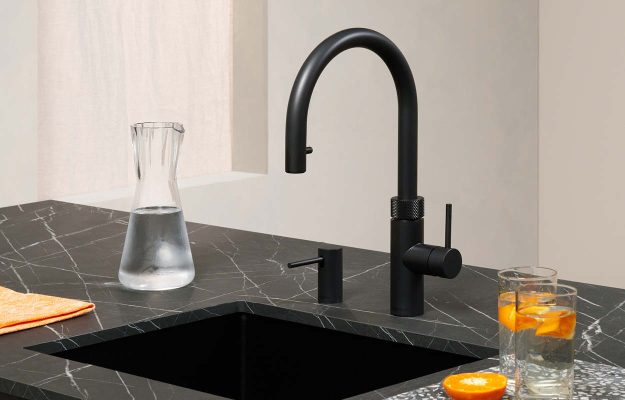 Exklusive schwarze Quooker auf dunkler Marmor-Arbeitsplatte mit integriertem Spülbecken – luxuriöse Ausstattungslösung im modernen Küchendesign.