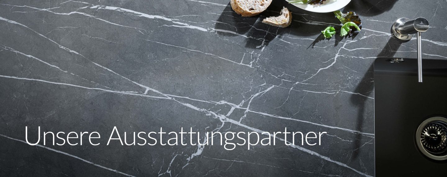 Elegante dunkelgraue Stein-Arbeitsplatte mit weißer Maserung, hochwertiger Edelstahlarmatur und schwarzer Spüle – hochwertige Materialien von Premium-Ausstattungspartnern.