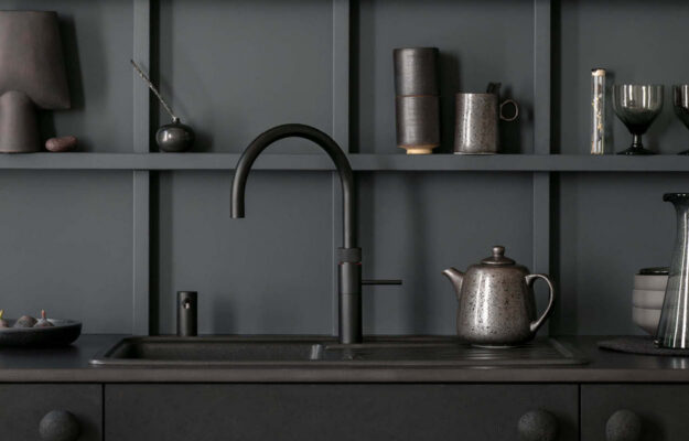 Design-Küchenarmatur von Quooker in Schwarz matt, kombiniert mit Spülbecken und stilvoller Küchenrückwand für moderne Optik