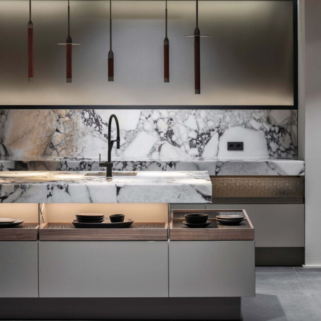 Moderne Poggenpohl Küche mit weißer Marmor-Kücheninsel, schwarzer Armatur und indirekter Beleuchtung im minimalistischen Design