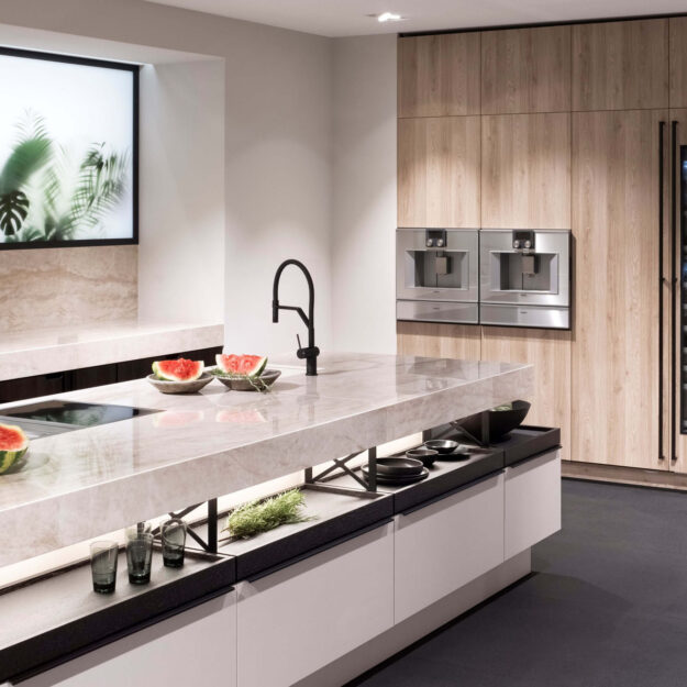 Moderne Poggenpohl Küche mit heller Naturstein-Kücheninsel, schwarzen Armaturen und integrierten Geräten in elegantem Wohnraum